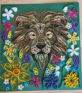 Quilling of a lion looking out through flowers found in Cornish hedges in march, against a green background