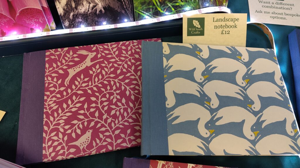 Landscape notebooks: hare and wren against magenta background with purple bookcloth; rabbit/duck pattern with blue bookcloth