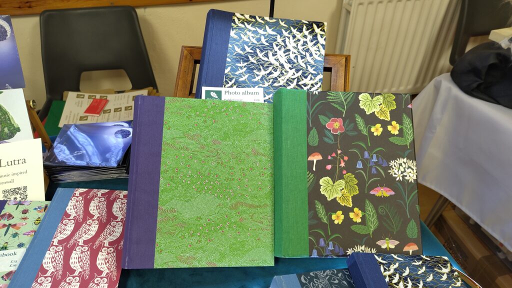Three photo albums: front right: green chiyogami with purple bookcloth; front right: woodland wild flowers with green bookcloth (padded); back: chiyogami cranes (gold highlights) with blue bookcloth